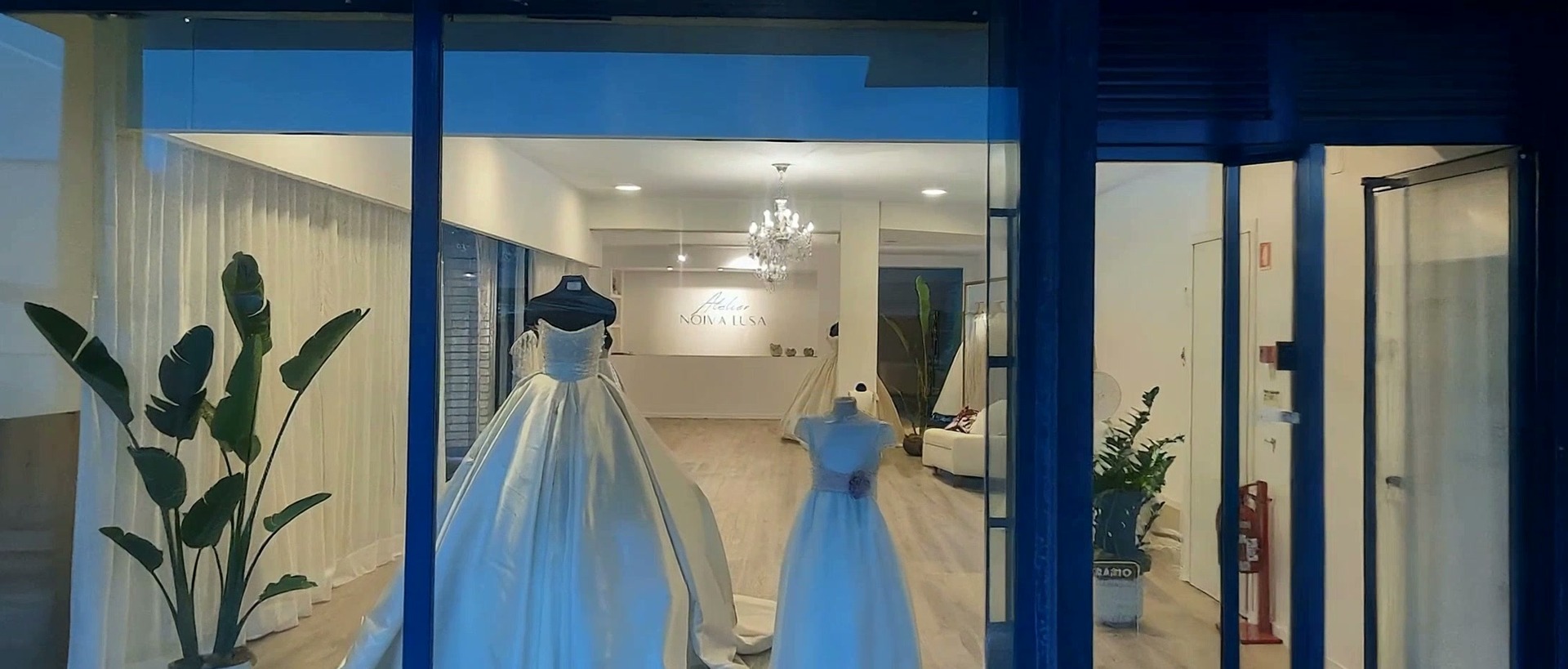 Atelier Noiva Lusa, vestido pendurado em cabide de madeira, luz quente filtrada
